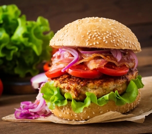 Appetizing Gourmet Hamburger Amidst Fresh Lettuce Leaves