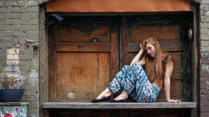 Redhead Model's Relaxed Pose in a Rustic Alleyway