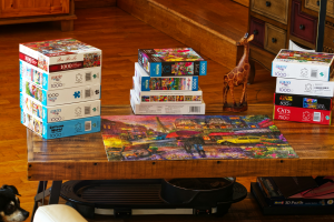 Unwinding with Puzzles: Wooden Giraffe Figurine amidst Jigsaw Boxes on a Wooden Table